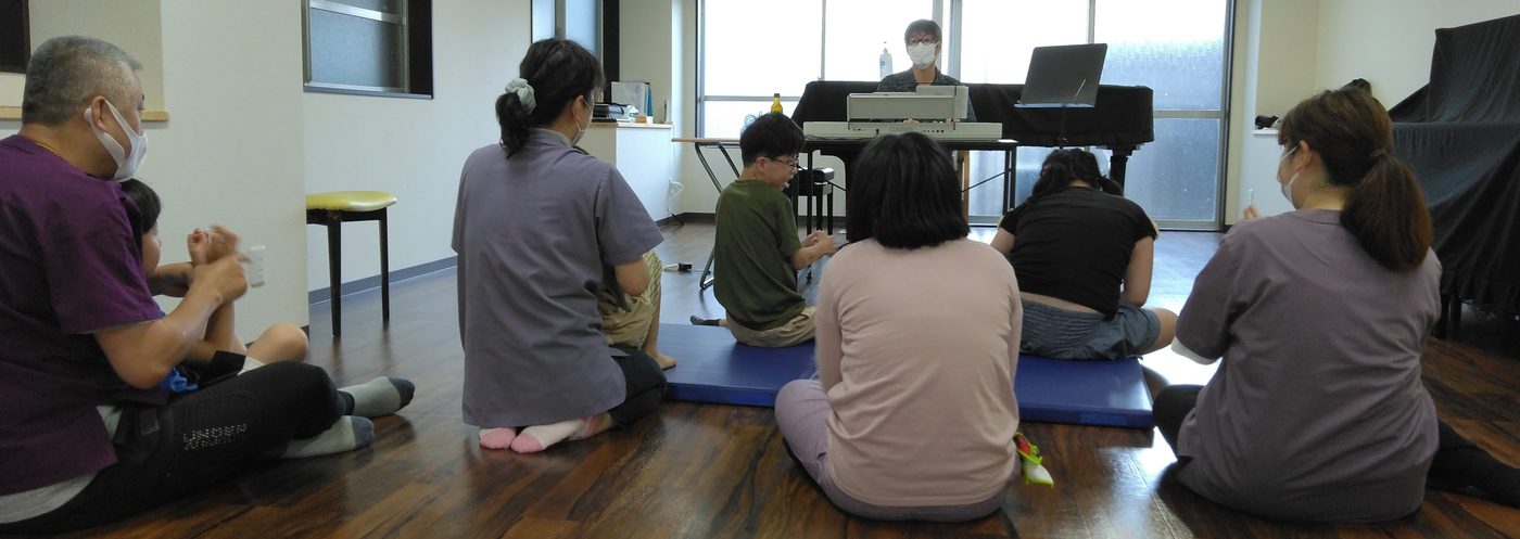 床にすわって、みんなで音楽やことばの療育を楽しむ様子