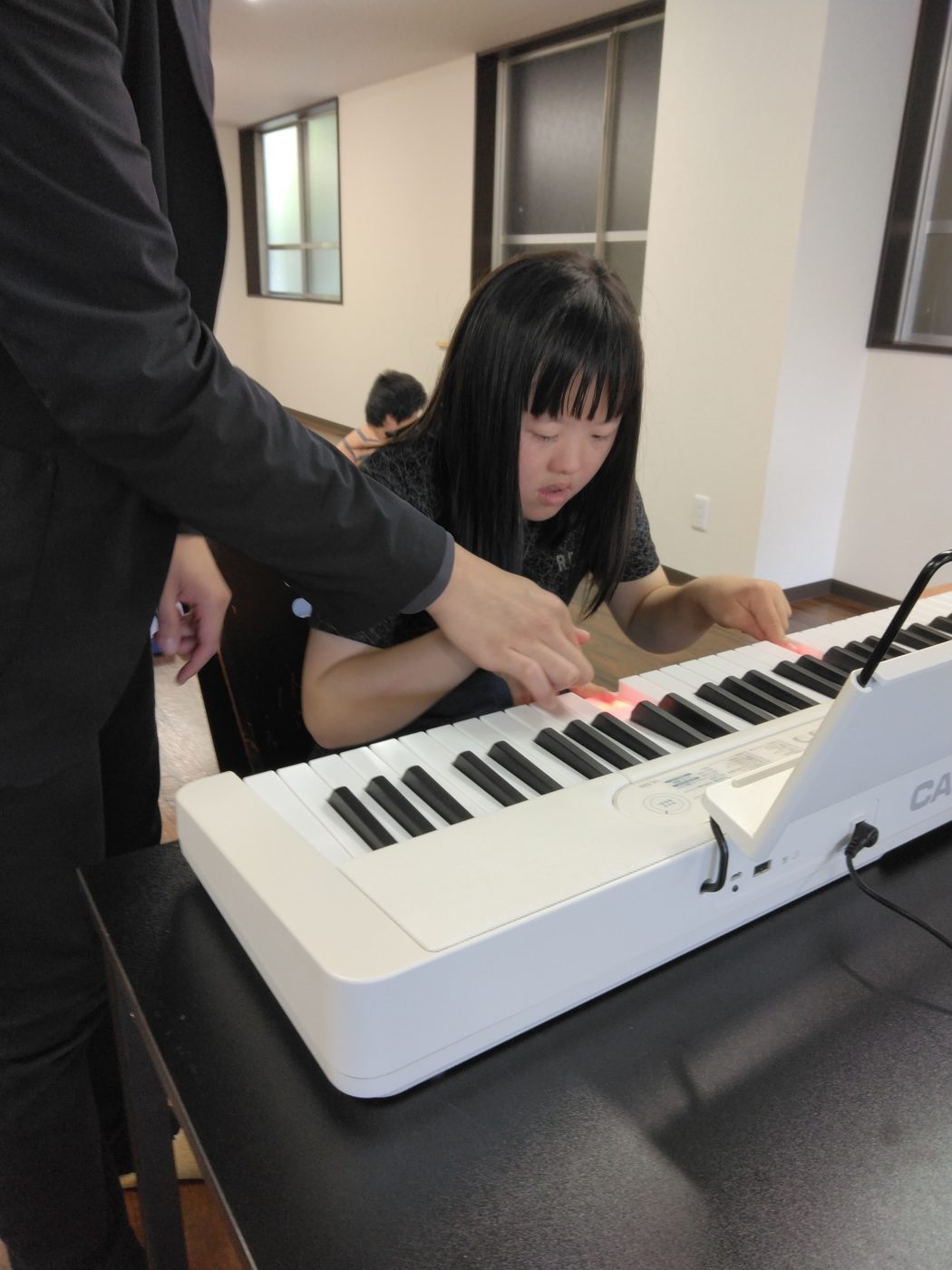 講師がそっと手を添え、鍵盤にふれるお子さん