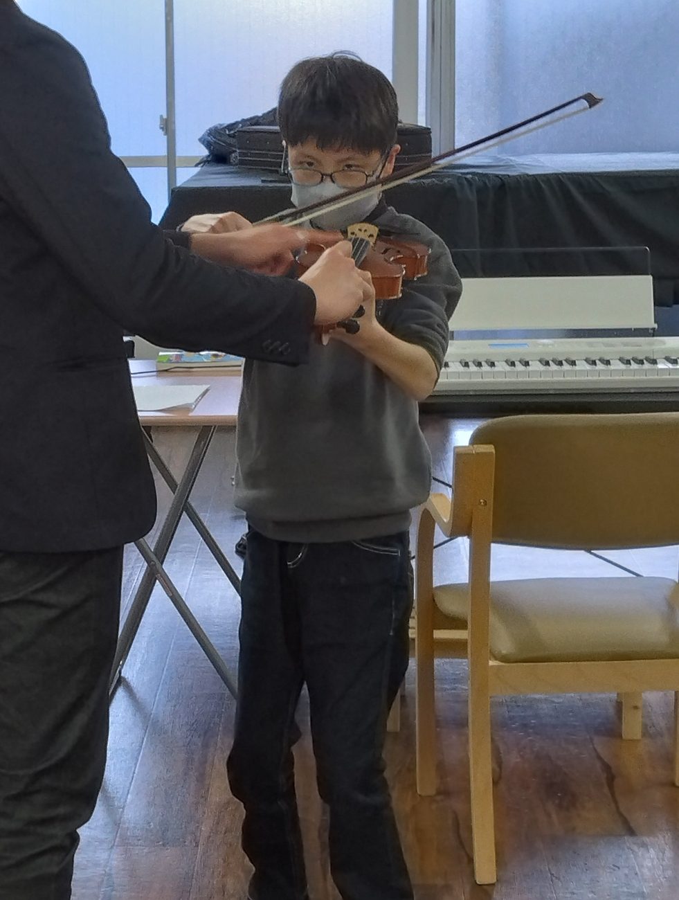 講師に手を添えられながらヴァイオリンを弾くお子さん